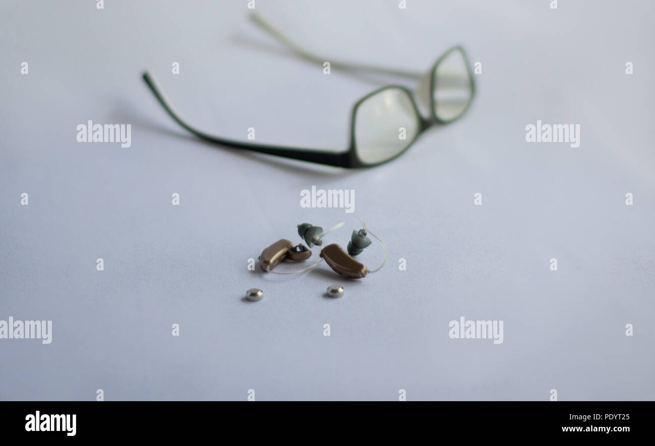 Hörgeräte und Batterien mit Brille im Hintergrund Stockfoto