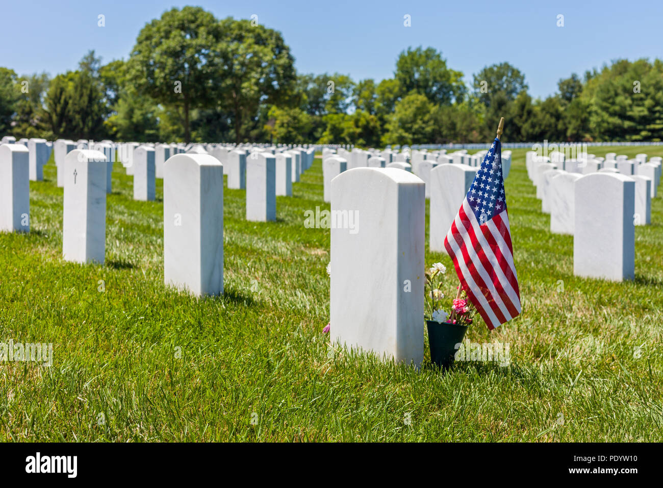 Die Vereinigten Staaten Nationalflagge mit weißen Grundsteine im Hintergrund im Camp Butler National Cemetery Stockfoto