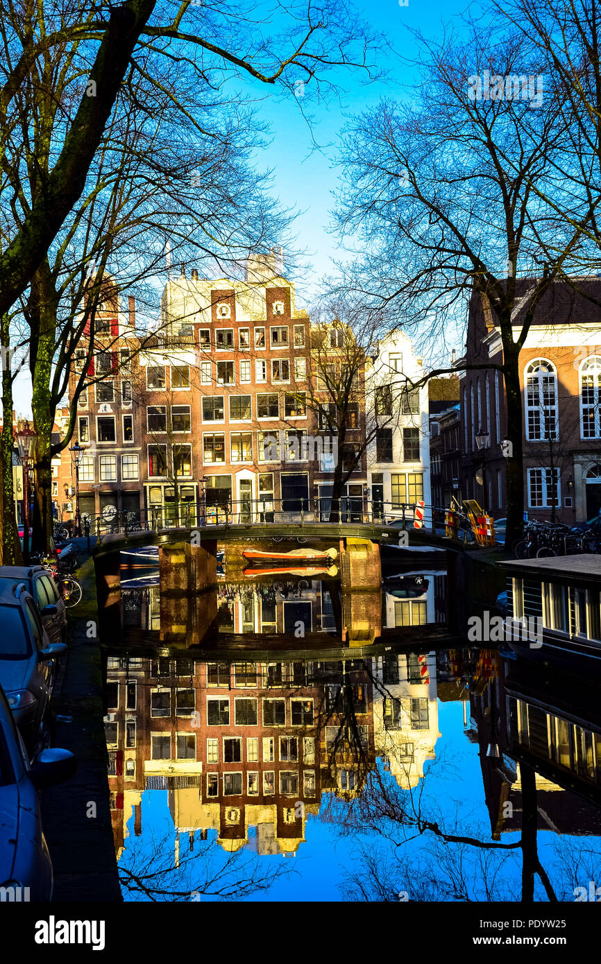 Blick nach unten einen Kanal mit Reflexionen an einem sonnigen Tag in Amsterdam, Niederlande Stockfoto