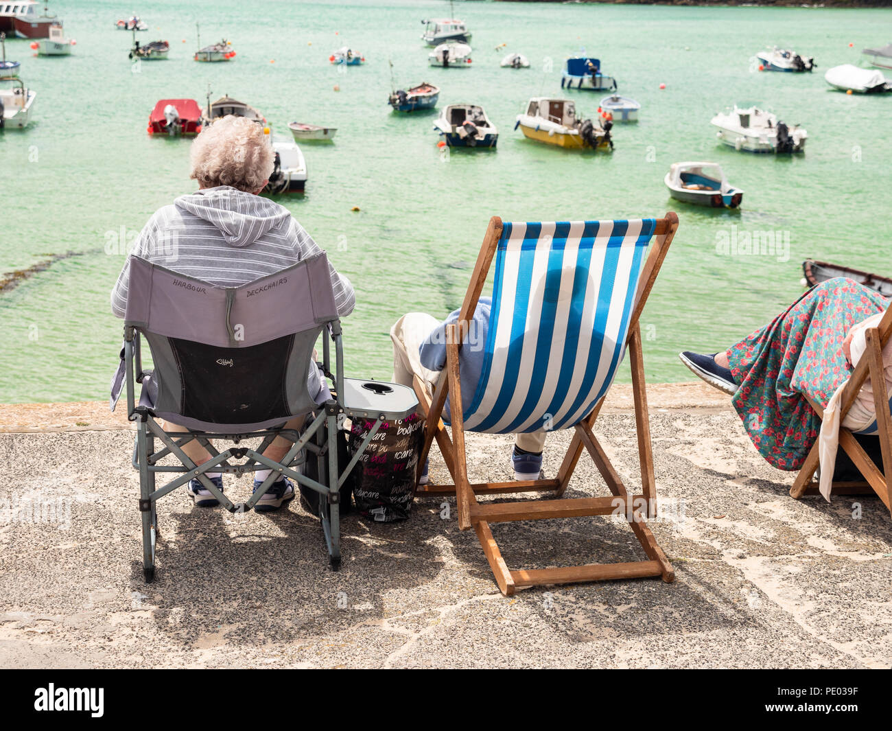 St. Ives, ENGLAND - Juni 19: OAP Paar sitzen in Liegestühlen die Sonne genießen, in St Ives Harbour. In St. Ives, England. Juni 2018 19. Stockfoto