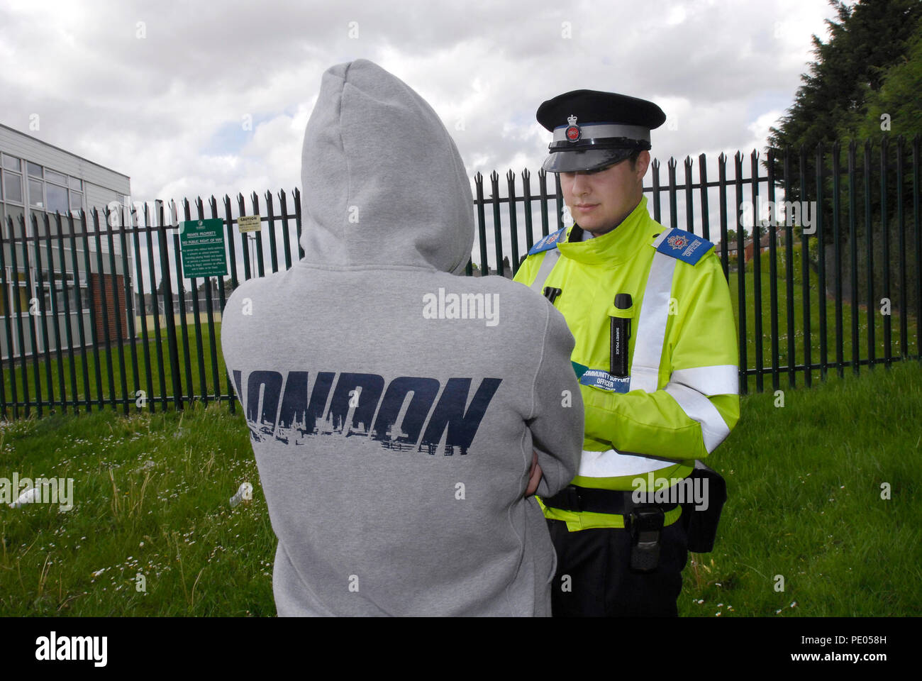 Ein Polizei Community Support Officer Fragen eine Jugend trägt ein Hoodie Stockfoto