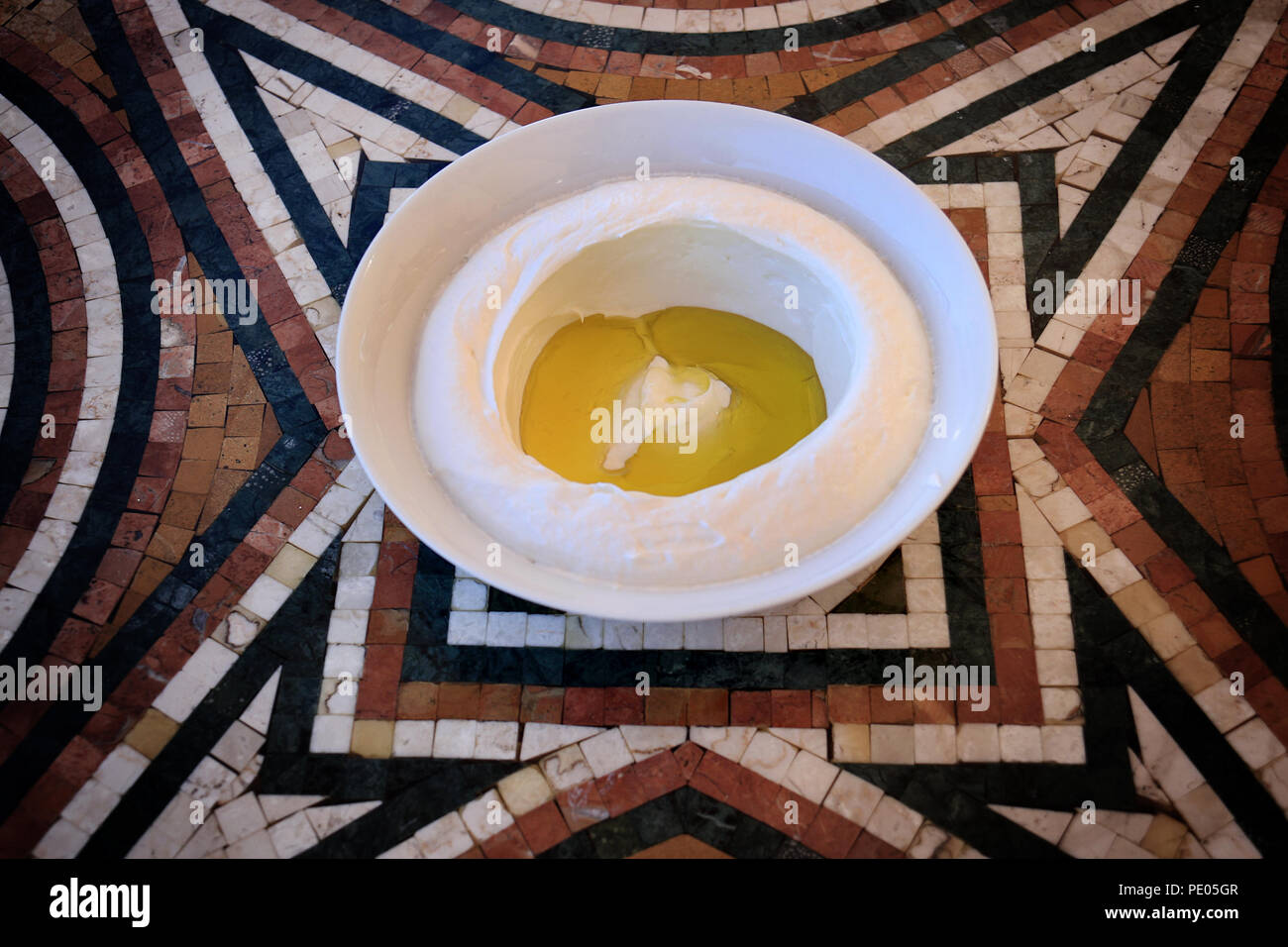 Eine frische labneh Schüssel mit Olivenöl auf einem Mosaik Tisch. Es ist eine traditionelle libanesische Frühstück. Stockfoto