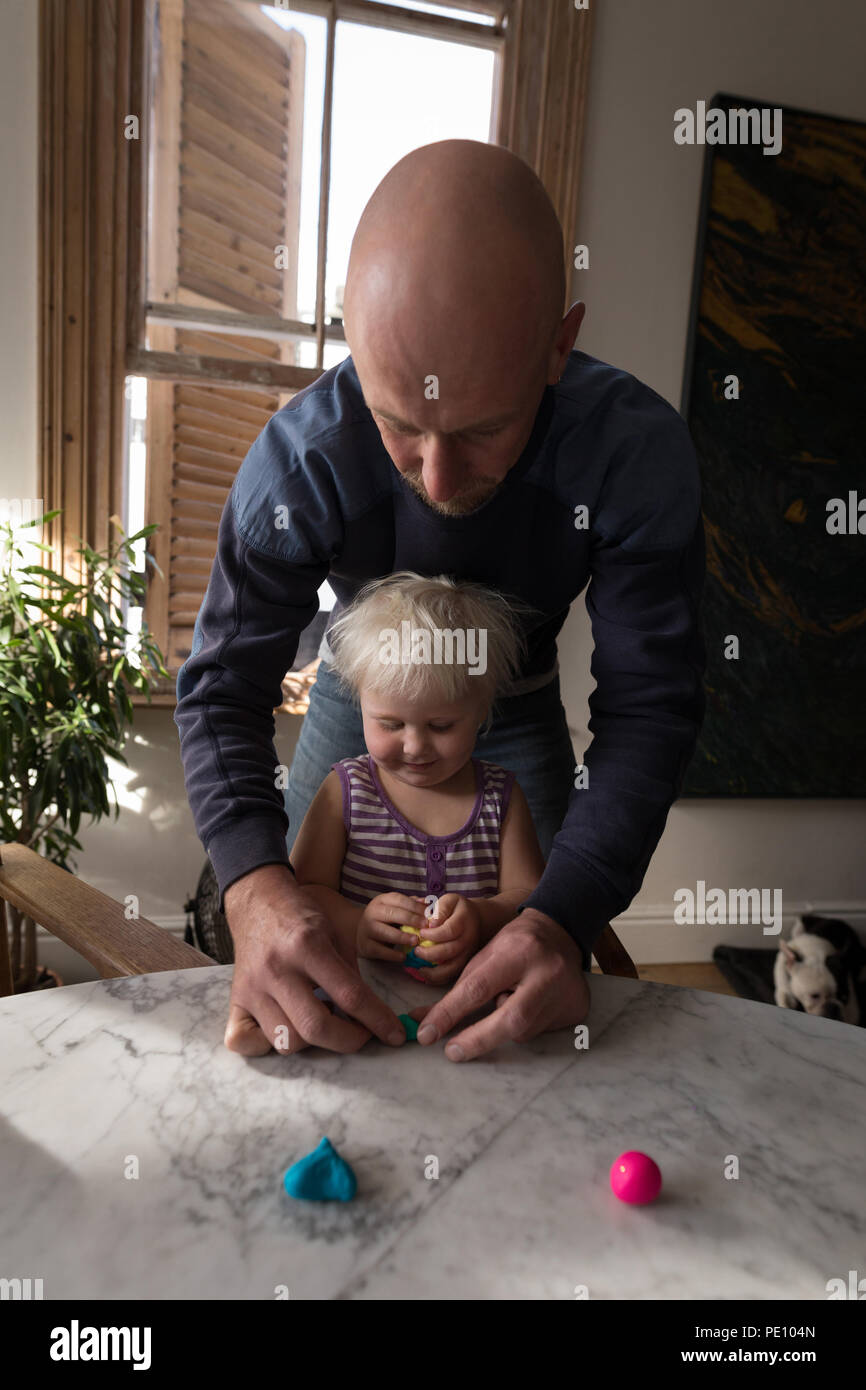 Vater und Baby Mädchen spielen mit Lehm im Wohnzimmer Stockfoto