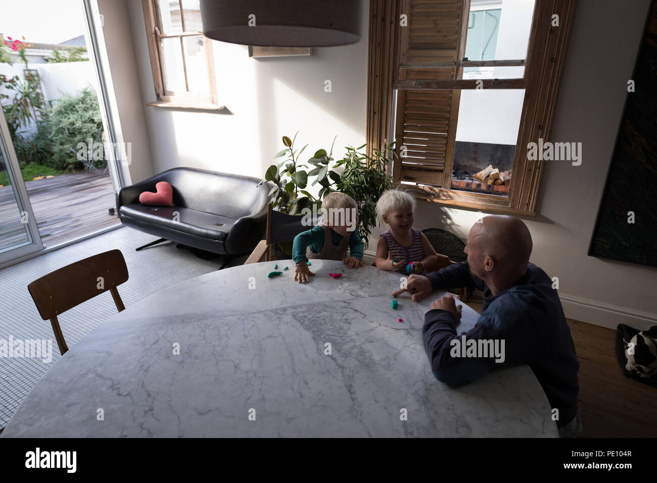 Vater und Kinder spielen mit Lehm im Wohnzimmer Stockfoto