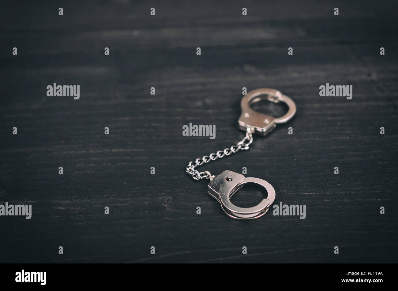 Recht und Gerechtigkeit Konzept, Handschellen auf schwarzem Holz- Hintergrund. Stockfoto