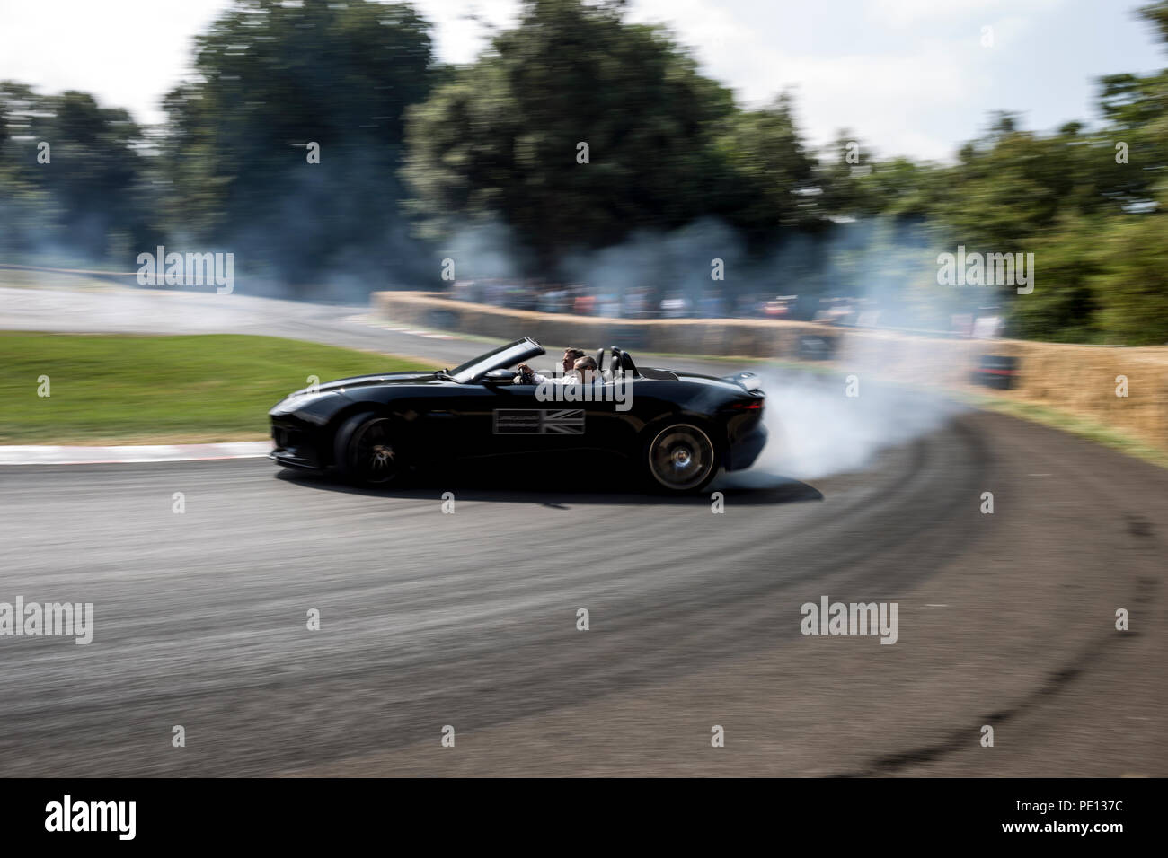 Ein Cabrio Jaguar Sportwagen spinnt seine Reifen, Erstellen von Rauch, auf einer Schiene am Goodwood Festival der Geschwindigkeit 2018. Stockfoto