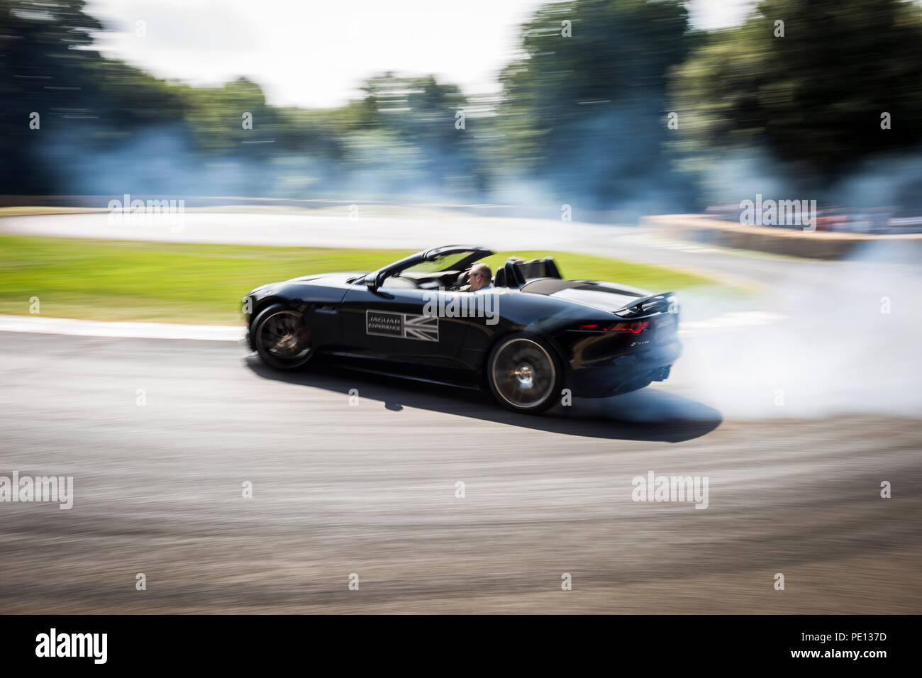 Ein Cabrio Jaguar Sportwagen spinnt seine Reifen, Erstellen von Rauch, auf einer Schiene am Goodwood Festival der Geschwindigkeit 2018. Stockfoto