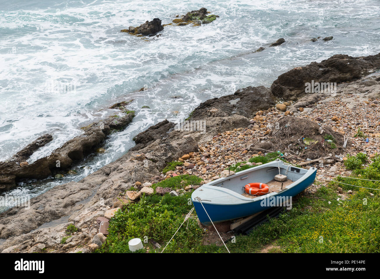 Kleines Ruderboot ist auf den Felsen an der Küste von Alghero entfernt Stockfoto