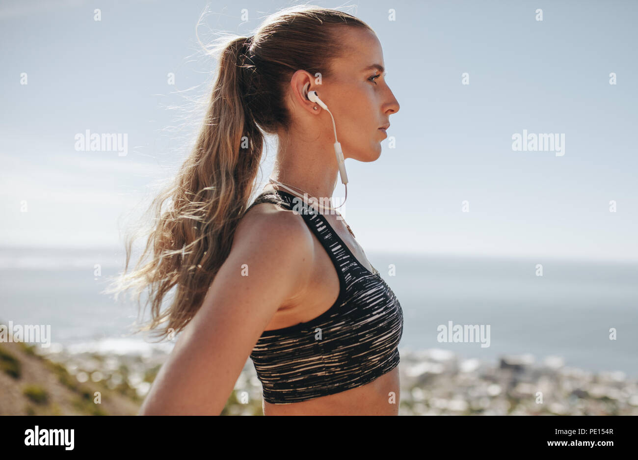 Profil anzeigen von weiblichen Trail Runner mit Ohrhörer im Freien. Frau runner Musik hören mit Ohrstöpsel nach der Ausführung in der wunderschönen Natur. Stockfoto