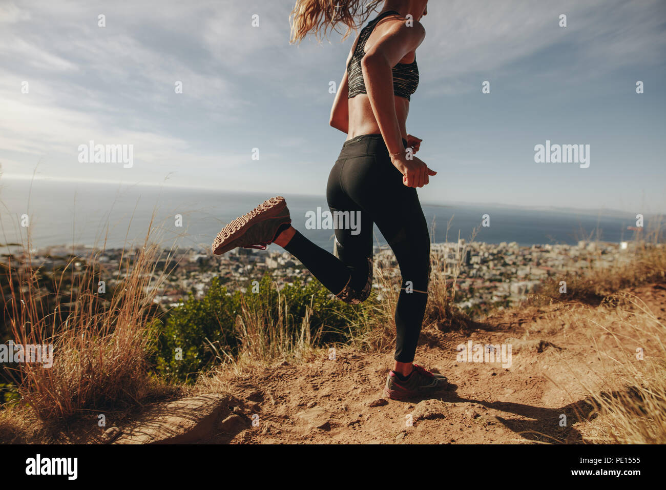 Gesunde, junge Frau, die auf Mountain Trail. Junge Frau joggen auf felsigen Weg auf einem Hügel. Stockfoto