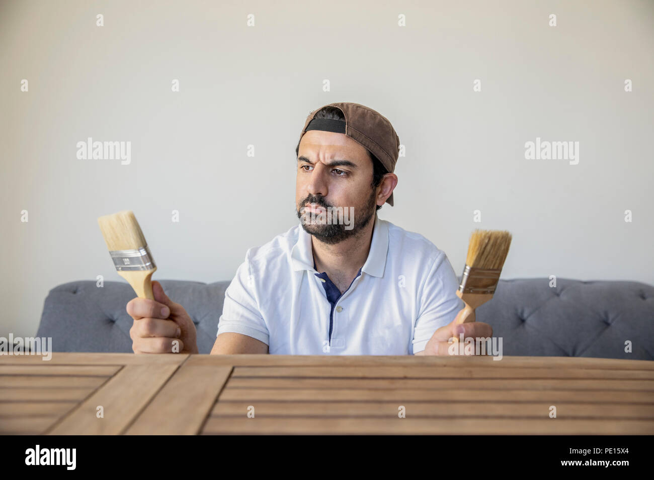 Arabischer Mann die Wahl ein Pint Pinsel einen Teak Tisch zu renovieren Stockfoto