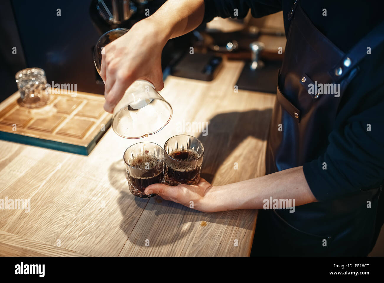 Junge männliche Barista macht frischen schwarzen Kaffee im Cafe. Barkeeper arbeiten in der Cafeteria, Barmixer espresso bereitet Stockfoto