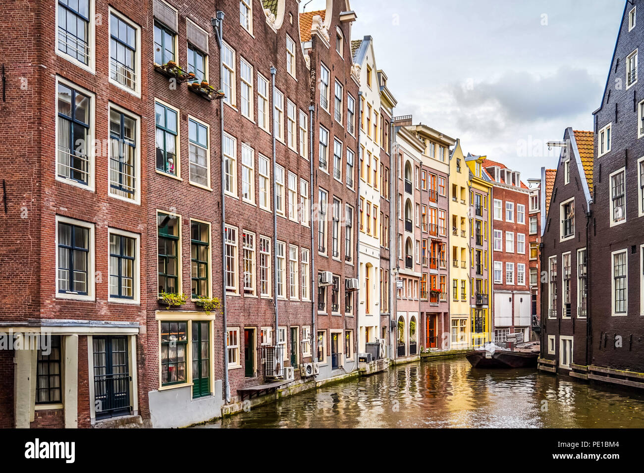 Historische Häuser auf dem Ouderzijds Achterburgwal Kanal im Rotlichtmilieu des alten Stadtzentrums von Amsterdam, Niederlande Stockfoto