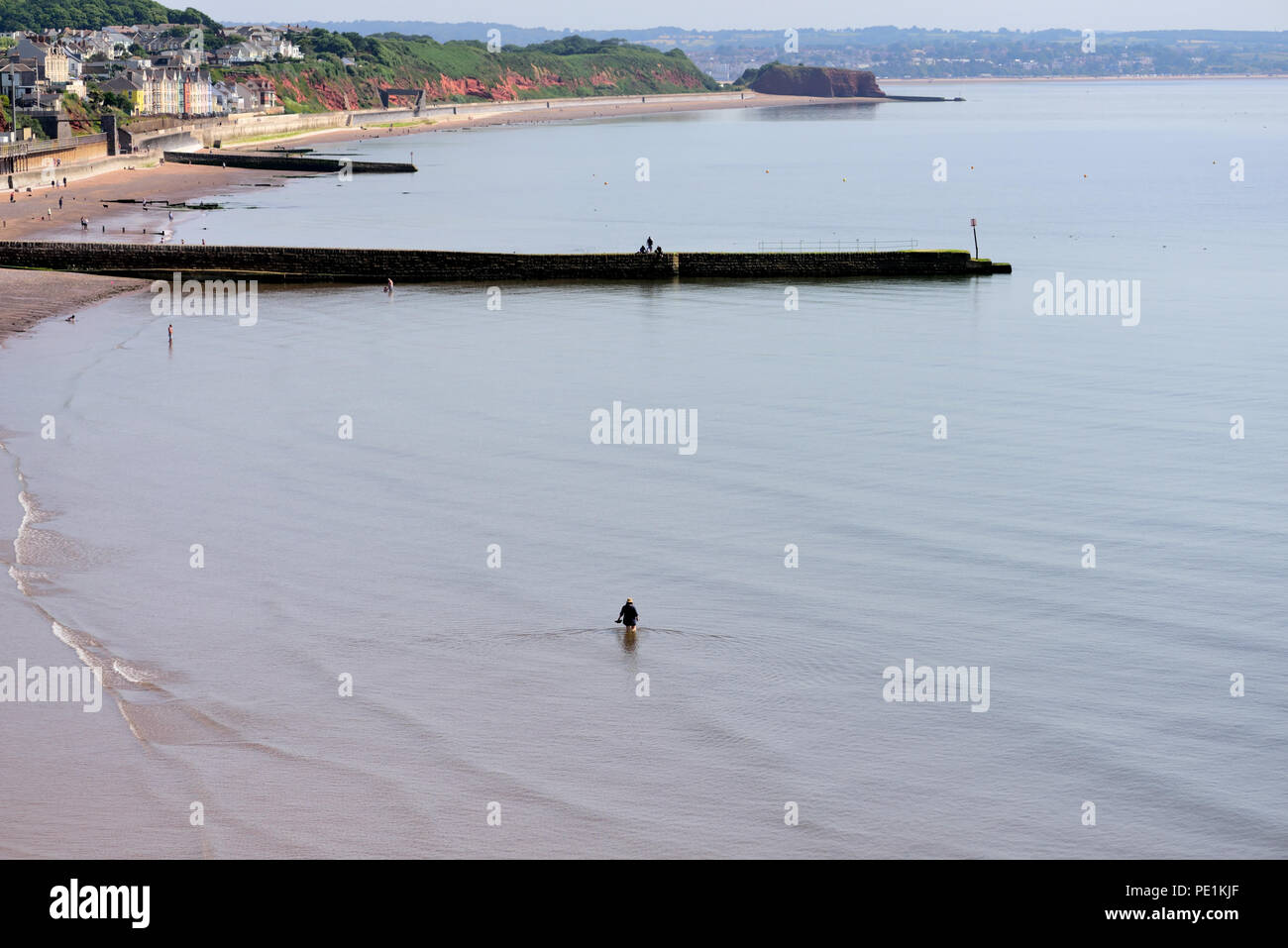 Ein einsamer Holiday Maker Paddeln im Meer bei Ebbe. Stockfoto