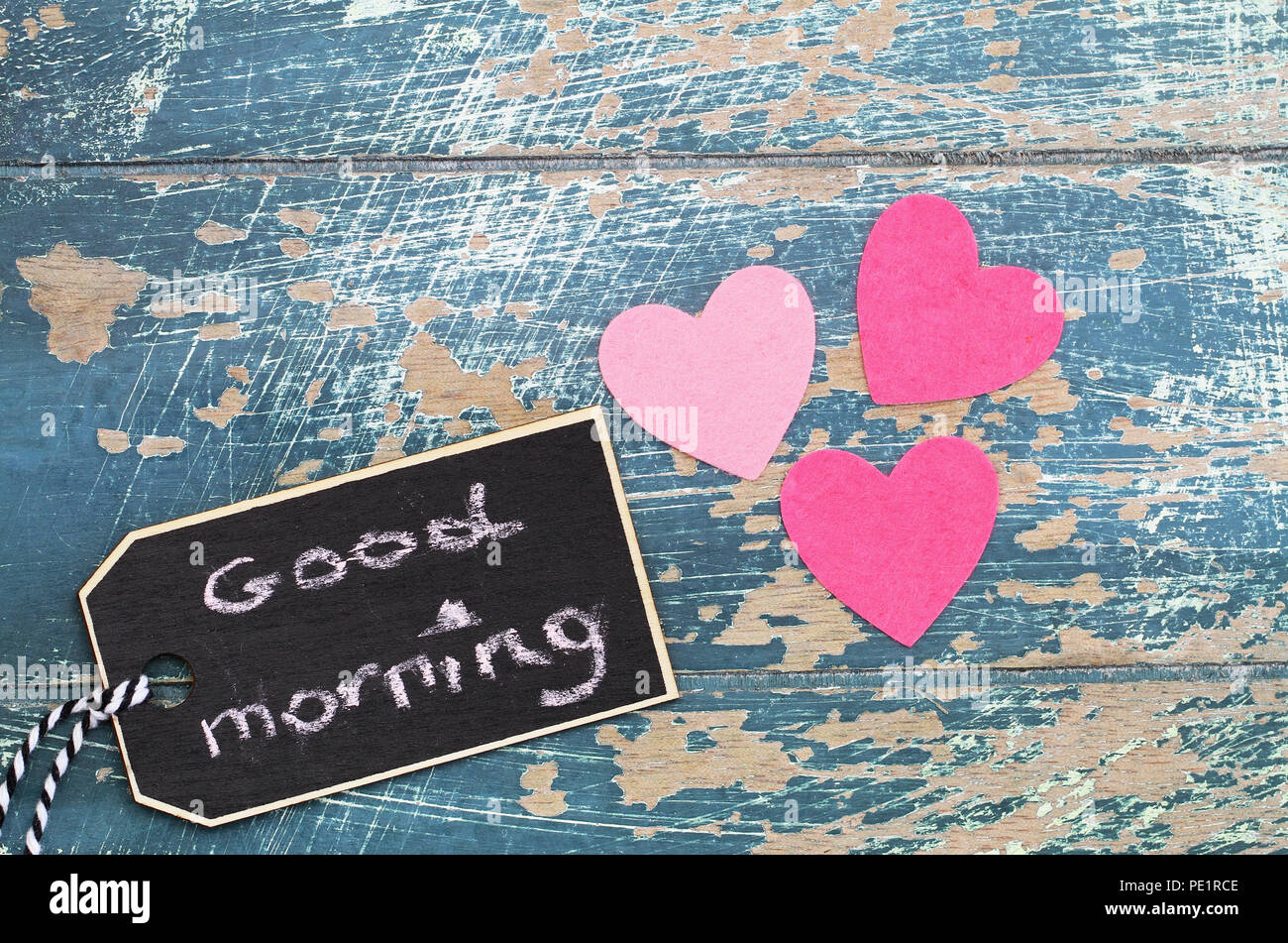 Guten Morgen auf mini Tafel mit drei rosa Herzen auf rustikale Oberfläche geschrieben Stockfoto