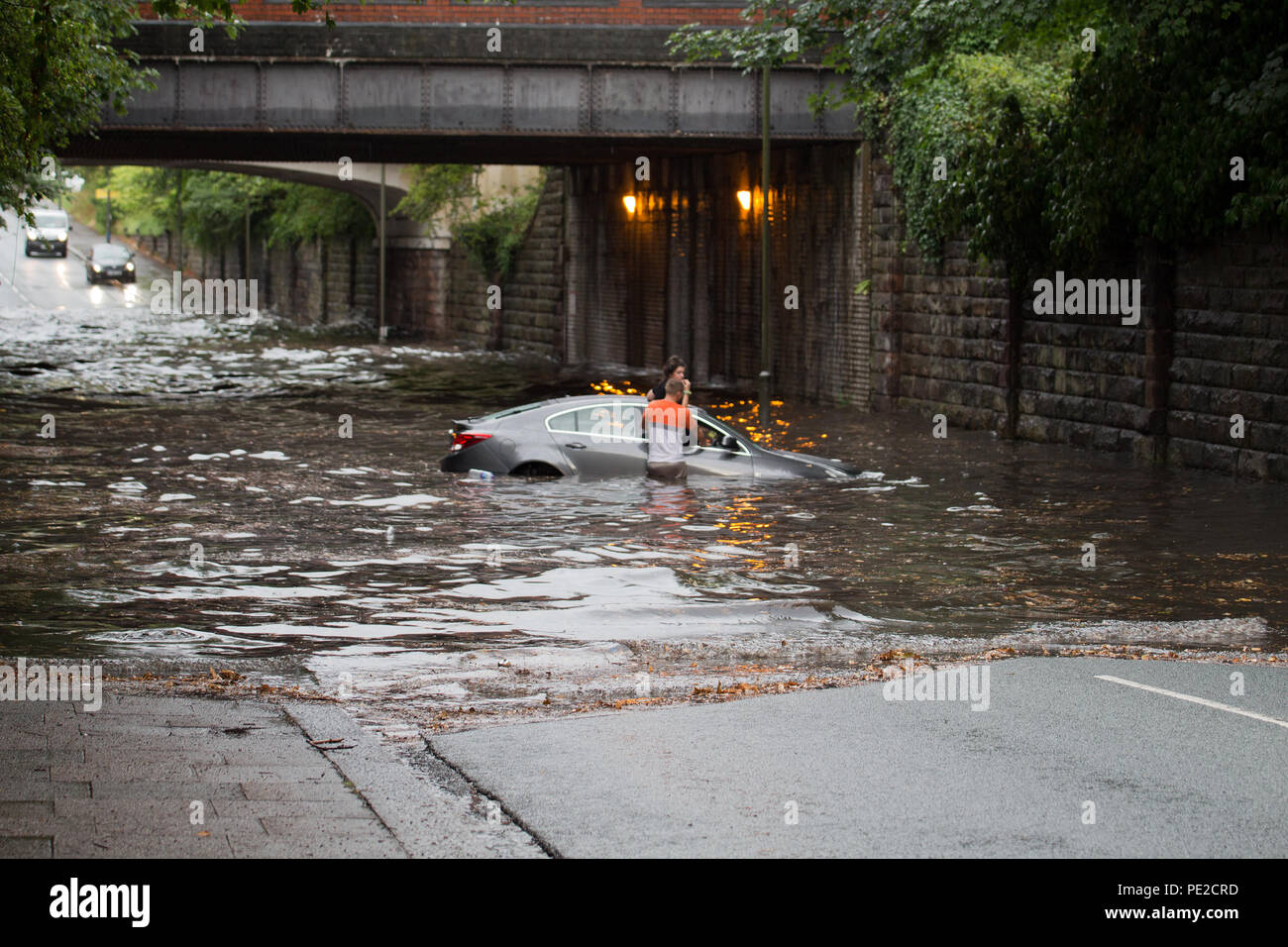 Liverpool, Großbritannien. 12 August, 2018. UK Wetter. Junge Paare sind in Ihrem Auto eingeschlossen, nachdem Überschwemmungen Liverpool schlagen. Die Paare wurden auf Queens Drive L 18 auf einem berüchtigten Sprung in der Straße gefangen, nach dem Kampf gegen das steigende Wasser sie schließlich durch das Wasser wateten gerade als die Feuerwehr eintraf. Credit: Ken Biggs/Alamy Leben Nachrichten. Stockfoto
