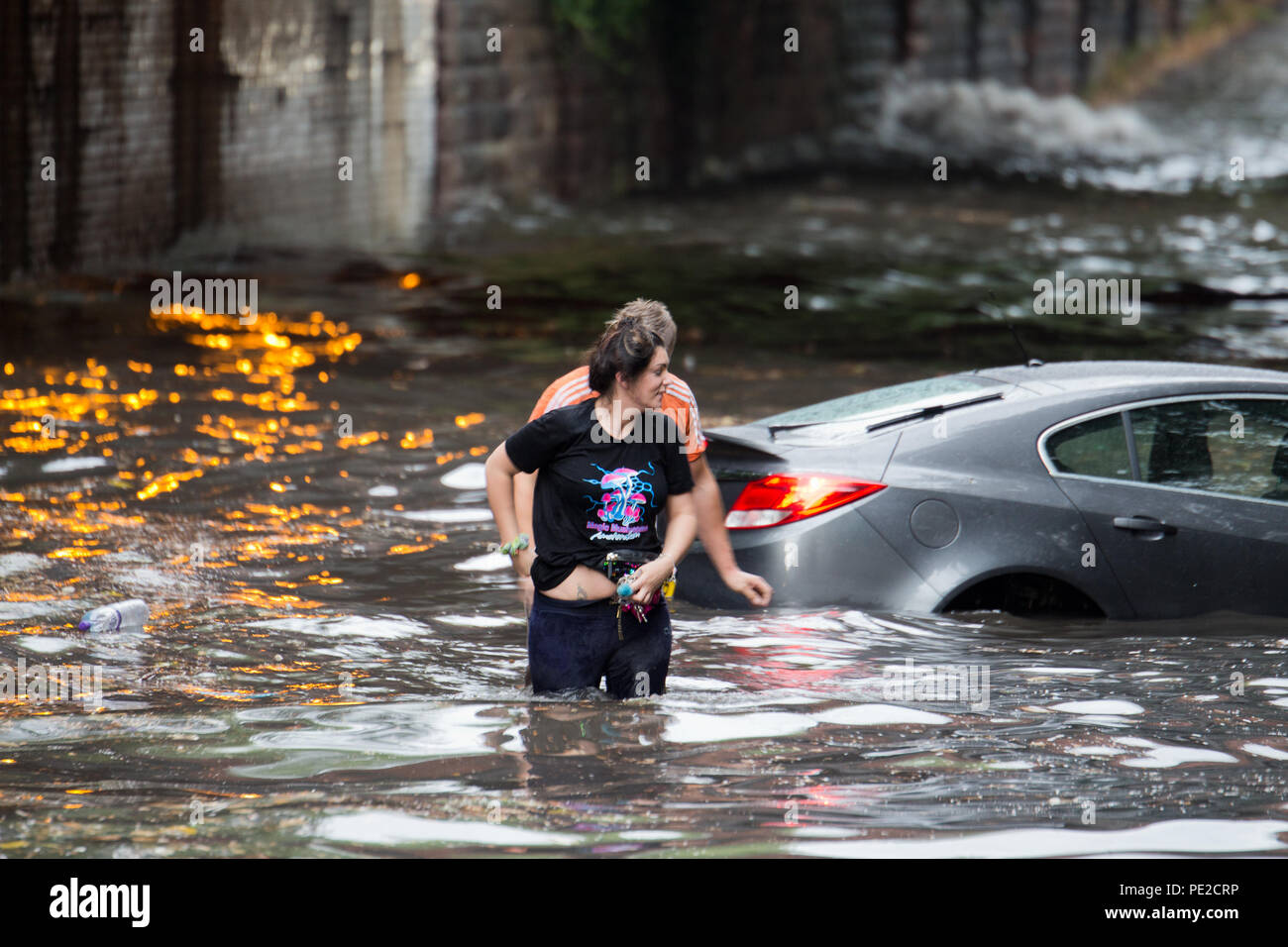 Liverpool, Großbritannien. 12 August, 2018. UK Wetter. Junge Paare sind in Ihrem Auto eingeschlossen, nachdem Überschwemmungen Liverpool schlagen. Die Paare wurden auf Queens Drive L 18 auf einem berüchtigten Sprung in der Straße gefangen, nach dem Kampf gegen das steigende Wasser sie schließlich durch das Wasser wateten gerade als die Feuerwehr eintraf. Credit: Ken Biggs/Alamy Leben Nachrichten. Stockfoto