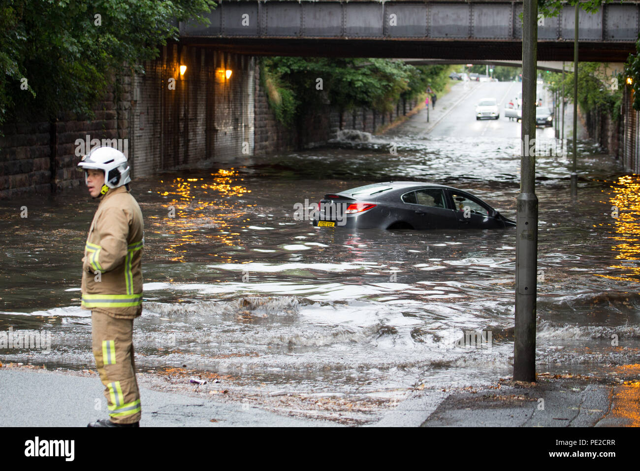 Liverpool, Großbritannien. 12 August, 2018. UK Wetter. Junge Paare sind in Ihrem Auto eingeschlossen, nachdem Überschwemmungen Liverpool schlagen. Die Paare wurden auf Queens Drive L 18 auf einem berüchtigten Sprung in der Straße gefangen, nach dem Kampf gegen das steigende Wasser sie schließlich durch das Wasser wateten gerade als die Feuerwehr eintraf. Credit: Ken Biggs/Alamy Leben Nachrichten. Stockfoto