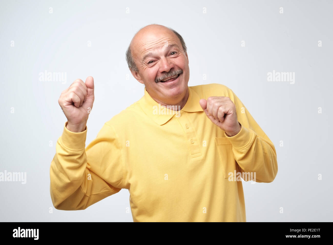 Reifen glücklicher Mann im gelben T-Shirt bewegen tanzen über weißen Hintergrund. Er genießt jeden Augenblick seines Lebens Stockfoto