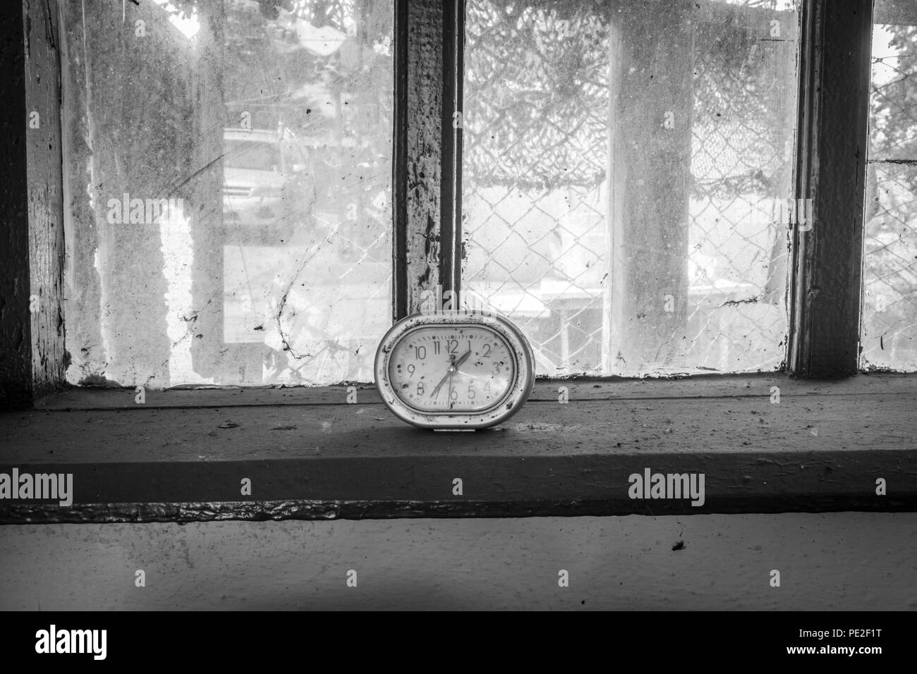 Alte Uhr auf dem Fenster eines verlassenen Hauses Stockfoto