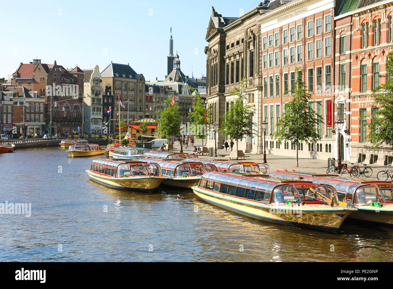 AMSTERDAM, NIEDERLANDE, 6. Juni 2018: Schöne Aussicht auf die Amstel mit vielen Touristen Schiffe und Universität Amsterdam auf dem Hintergrund Stockfoto