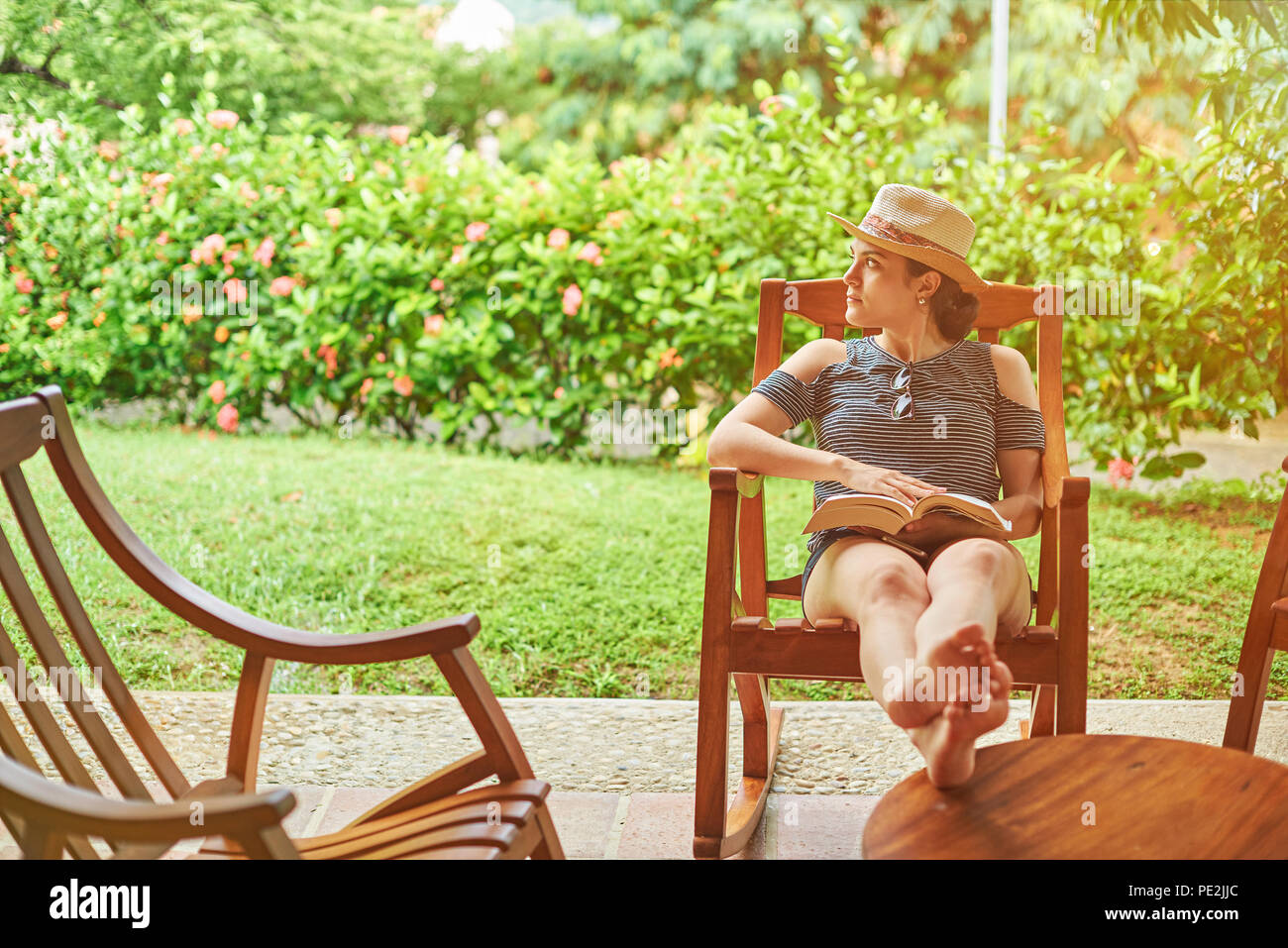 Frau im Urlaub Thema. Lesen buchen Sie im schönen Sommergarten Stockfoto