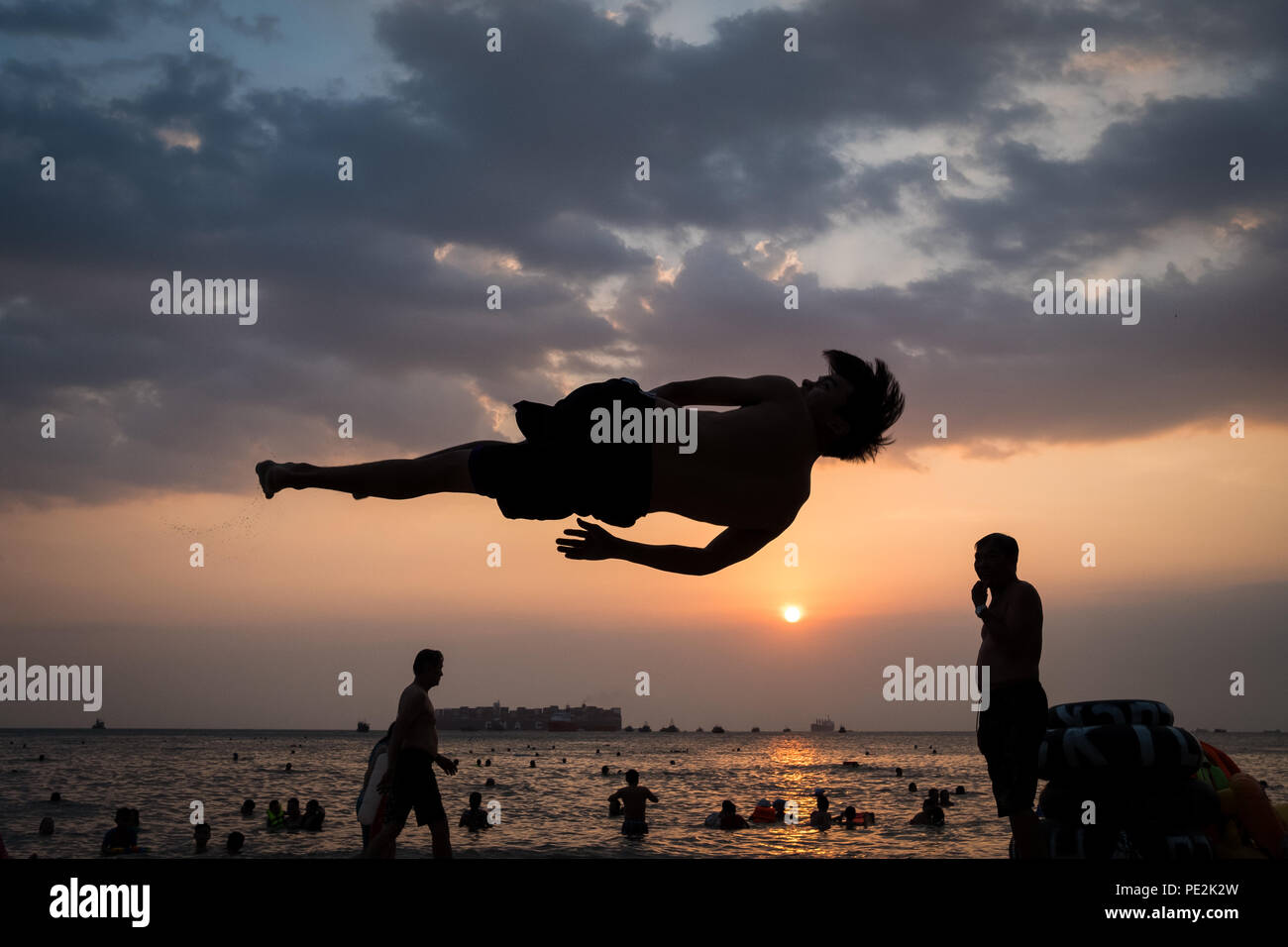 Ein junger Mann üben Flips, fast zu fliegen, bei Sonnenuntergang am Strand, Vung Tau, Vietnam Stockfoto