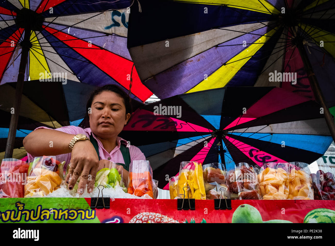 Eine Frucht der Anbieter unter bunten Sonnenschirmen in Bangkok, Thailand. Stockfoto