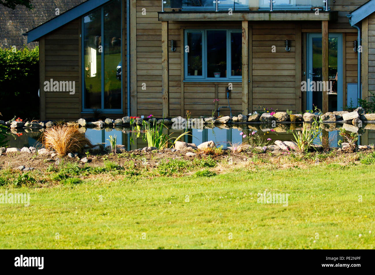 Zeder und Glas Haus mit einem großen Teich Stockfoto