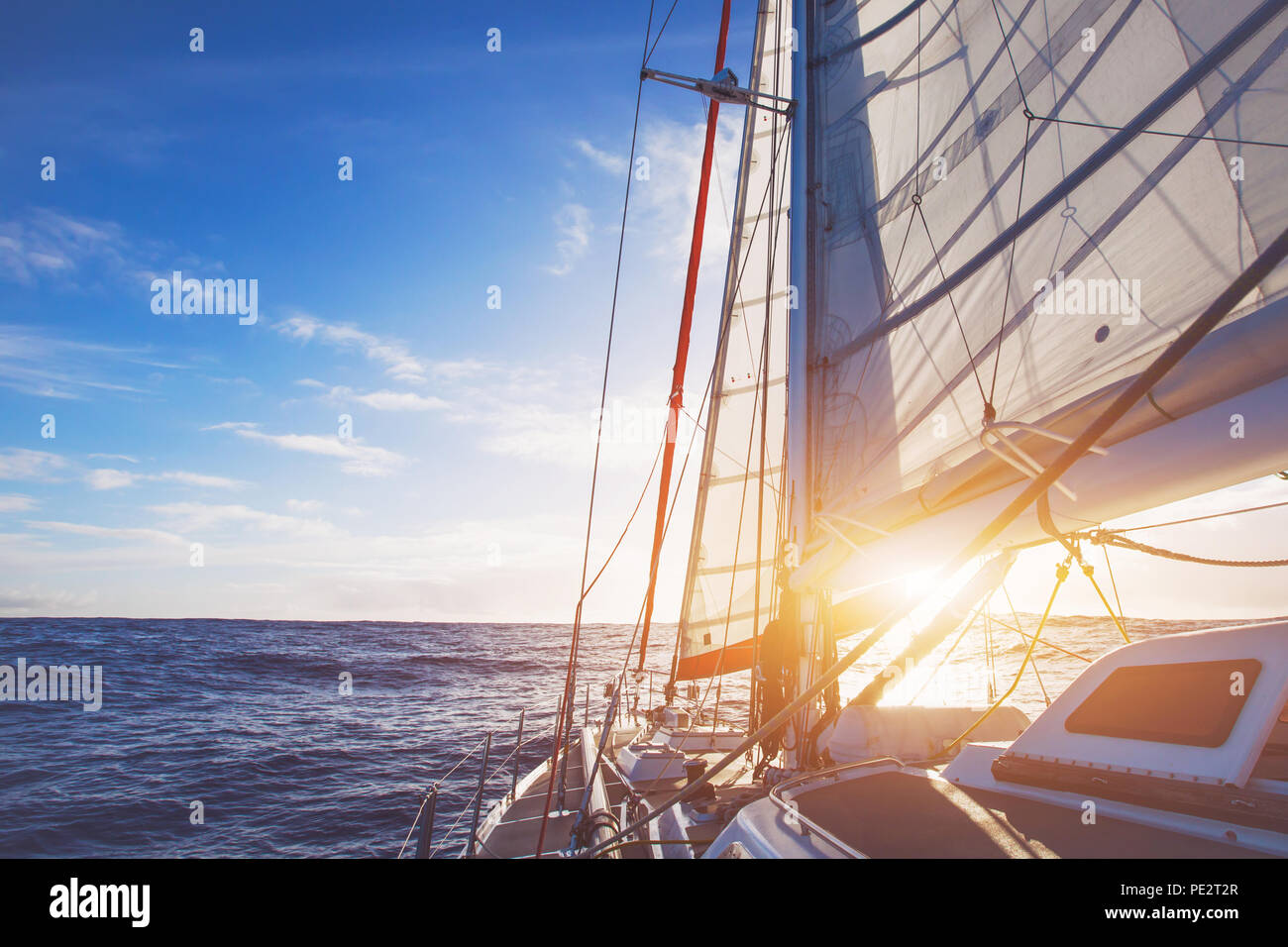 Segelboot im offenen Meer bei Sonnenuntergang, schöne luxuriöse Yacht Kreuzung Ozean Stockfoto