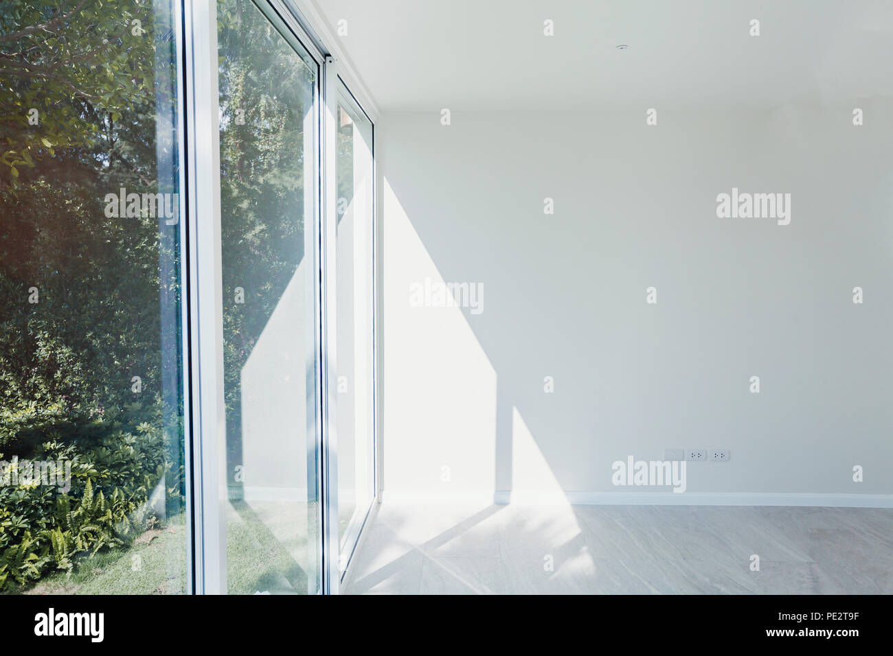 Leere sonnigen Zimmer mit weiß gestrichenen Wänden, großen Fenstern und modernen Holzfußboden Parkett, neue Wohnung im Bau Stockfoto