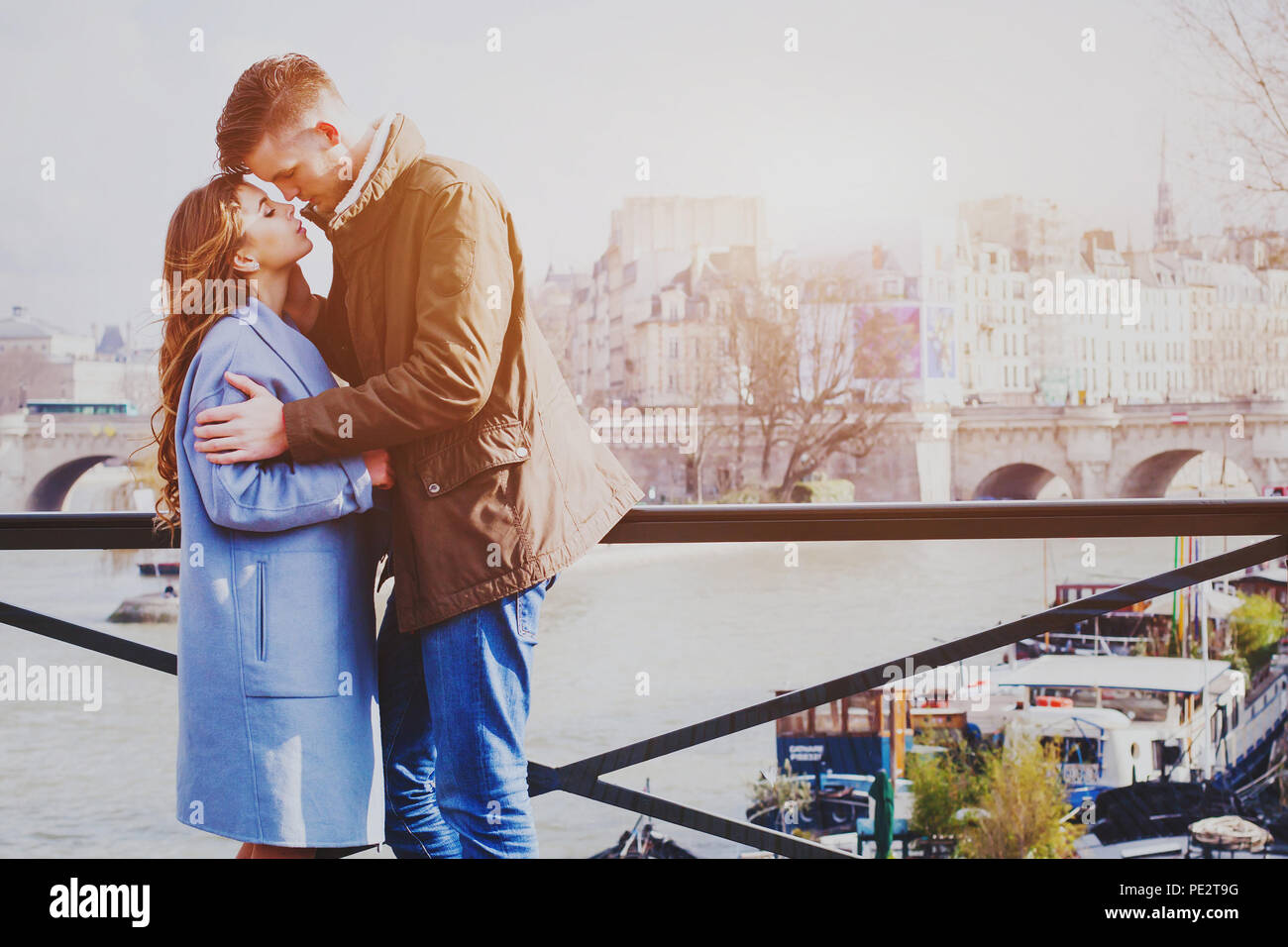 Liebe Paar Küssen auf der Straße in Paris, romantischen Moment in Flitterwochen, glücklich, liebevolle junge Mann und die Frau auf der Brücke über den Fluss Seine Stockfoto
