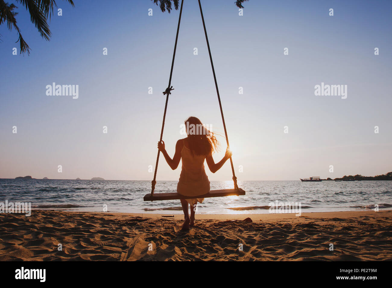 Happy Sommer Strand Urlaub, schönes Mädchen auf Schaukel an sonnigen Sonnenuntergang, Reise Urlaub am Meer genießen, Glück Konzept Stockfoto