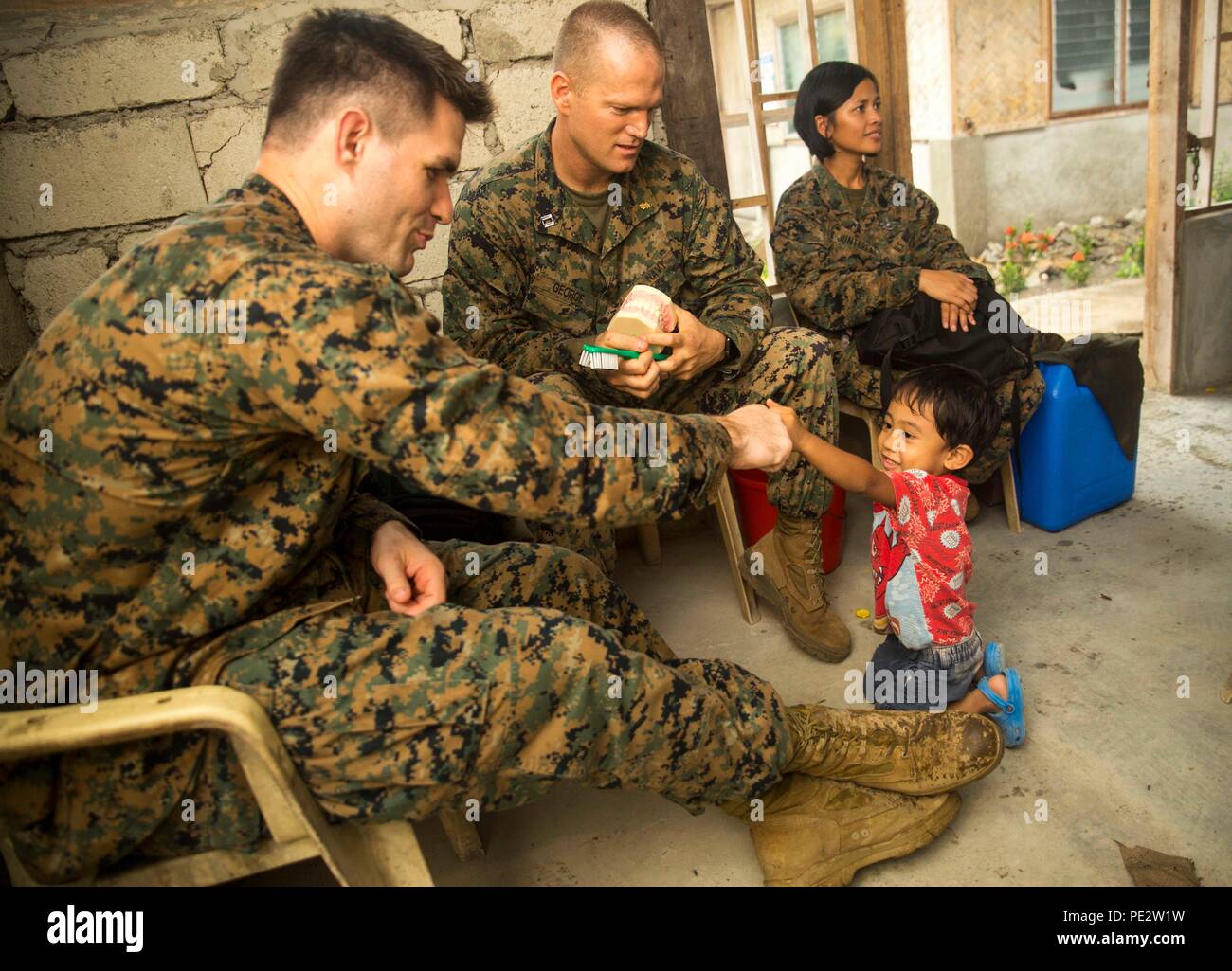 Navy Leutnant Peter Willett, kooperative Gesundheit Engagement (CHE) Offizier mit Sitz Regiment, 3d Marine Logistics Group, III Marine Expeditionary Force, Faust Stößen ein Filipino kind Sept. 23, nach ihm beibringen, wie Zähne richtig putzen während einer Kooperative Gesundheit Engagements (CHE) als Teil der amphibische Landung Übung 2015 (PHIBLEX 15). 15 PHIBLEX ist eine jährliche, bilateralen Training durch Mitglieder der Streitkräfte der Philippinen neben US Marine und Marine Kräfte durchgeführt. Es konzentriert sich auf die Stärkung der Partnerschaft und Beziehungen zwischen den beiden Nationen in einem Stockfoto