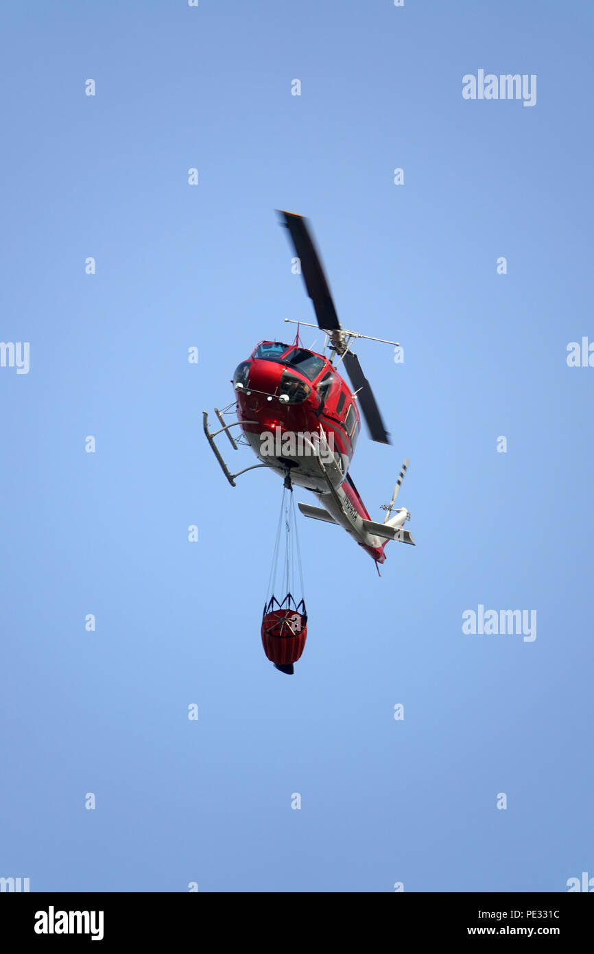 Ein Hubschrauber trägt einen Wassereimer, um Waldbrände zu bekämpfen. Hubschrauber sind eine primäre Antenne support system Waldbrände zu bekämpfen, indem sie Wasser auf einem Stockfoto