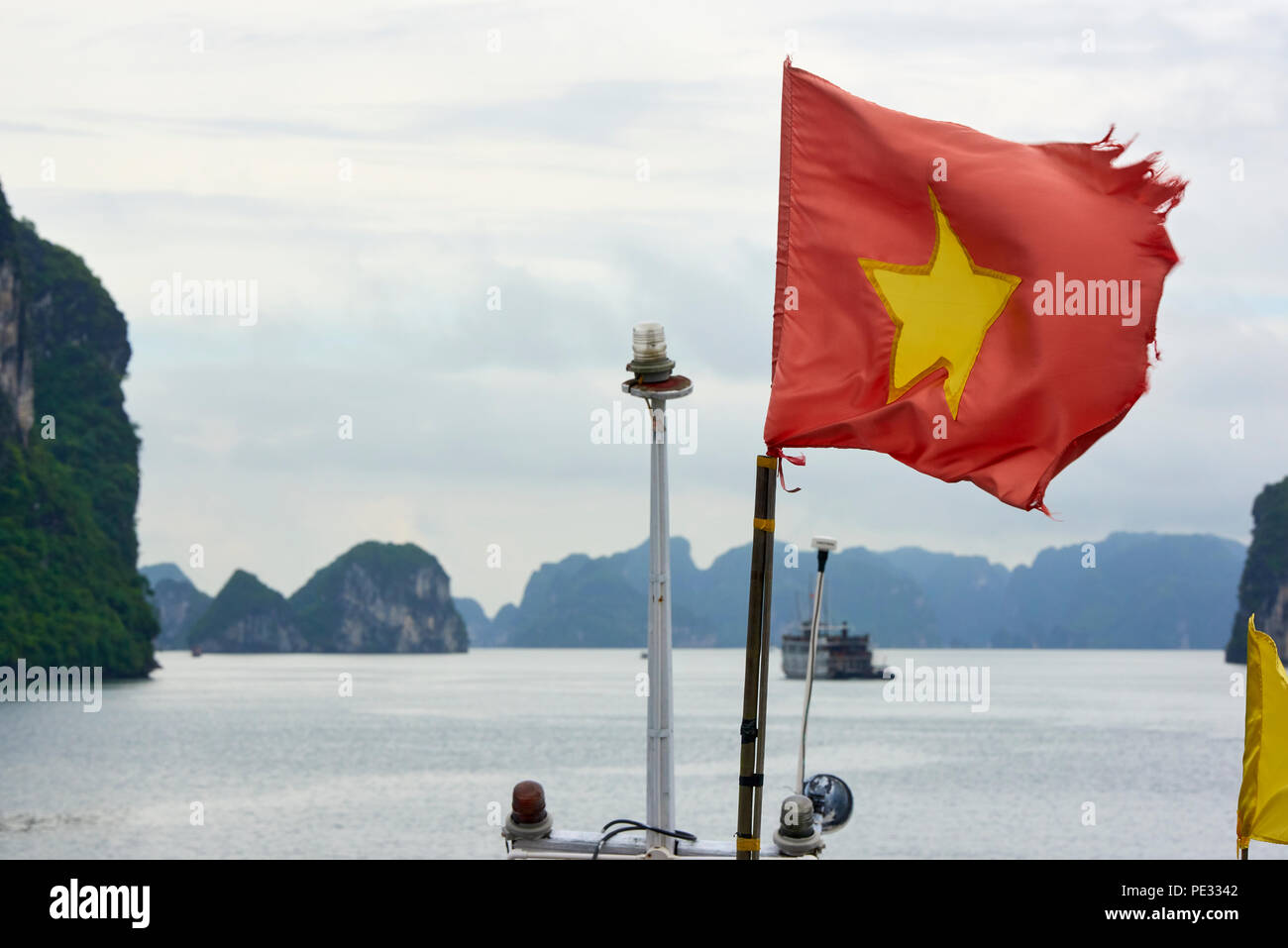 Ein ausgefranstes Vietnamesische flag schwanken im Wind in Halong Bay, North Vietnam. Stockfoto