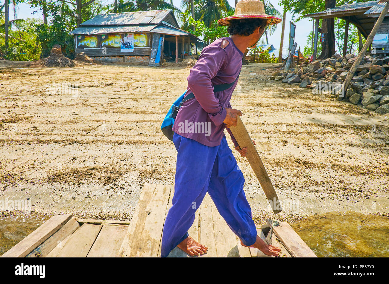 THAZIN, MYANMAR - 28. FEBRUAR 2018: Die raftman verwendet die Planke aus der Bank des Flusses mit Blick auf die Häuser des Dorfes auf Hintergrund zu drängen, auf Februar Stockfoto