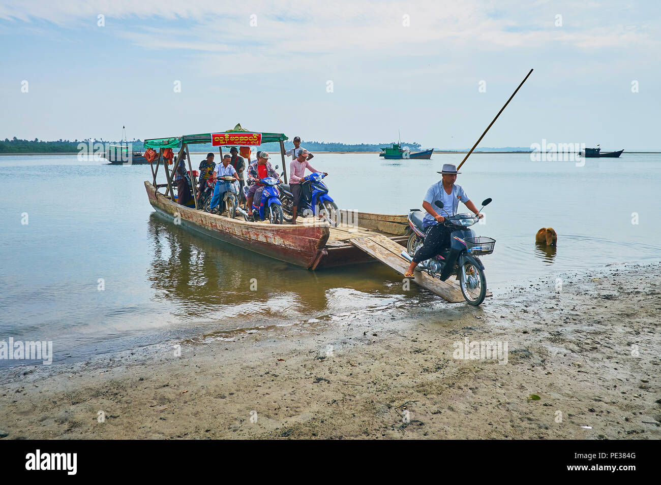 CHAUNG THA, MYANMAR - 28. FEBRUAR 2018: Die Passagiere mit Motorrädern verlassen den überfüllten Floß-Fähre über den Fluss Kangy, am 28. Februar in Chaung Stockfoto