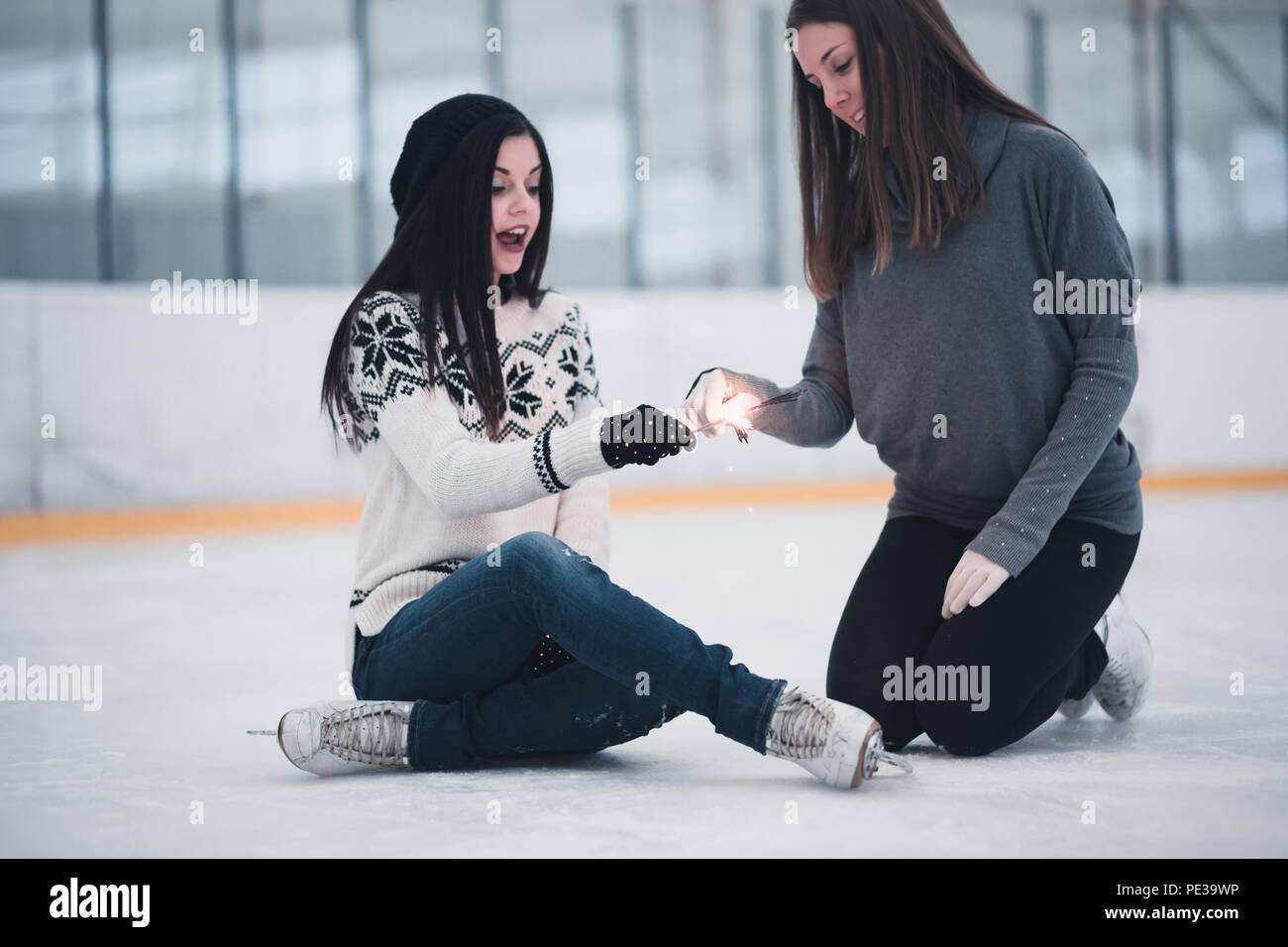 Freunde auf schlittschuhen an der Eislaufbahn holding Funken und Spaß zu haben. Selektiver Fokus auf die Hände. Stockfoto
