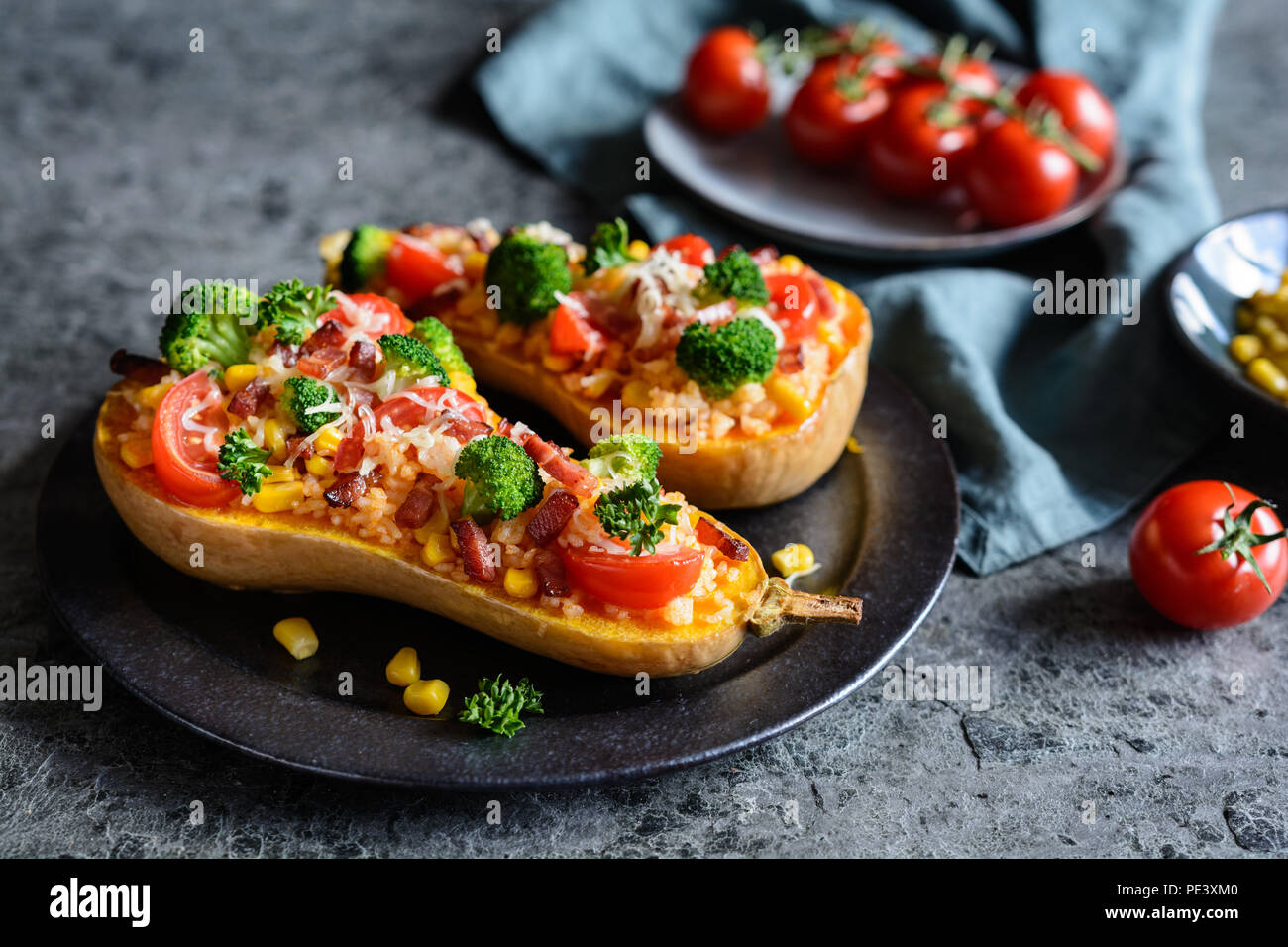 Gebratener Kürbis gefüllt mit Reis, Schinken, Broccoli, Tomaten, Mais und Käse Stockfoto