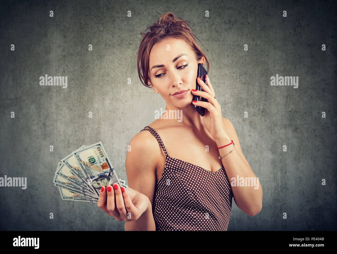 Junge selbstbewusste Frau sprechen auf dem Smartphone Sorglosigkeit über Roaminggebühren für Holding Haufen Dollar Stockfoto