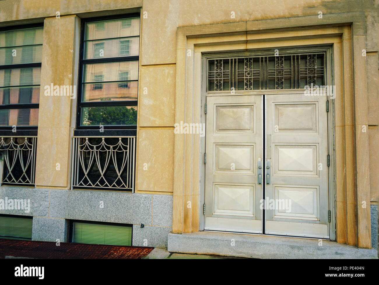 Interessante Silber doppel Türen und Fenster zu einer farbenfrohen Innenstadt Gebäude. Stockfoto