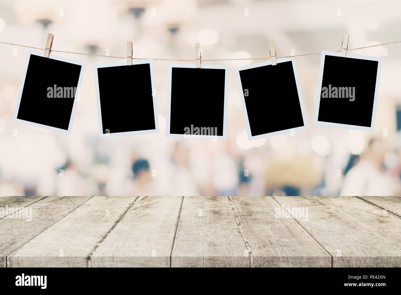 Leere Holz Tisch und Instant Foto hängen an blur Bild Hintergrund von Personen anzeigen Montage für Produkt. Stockfoto