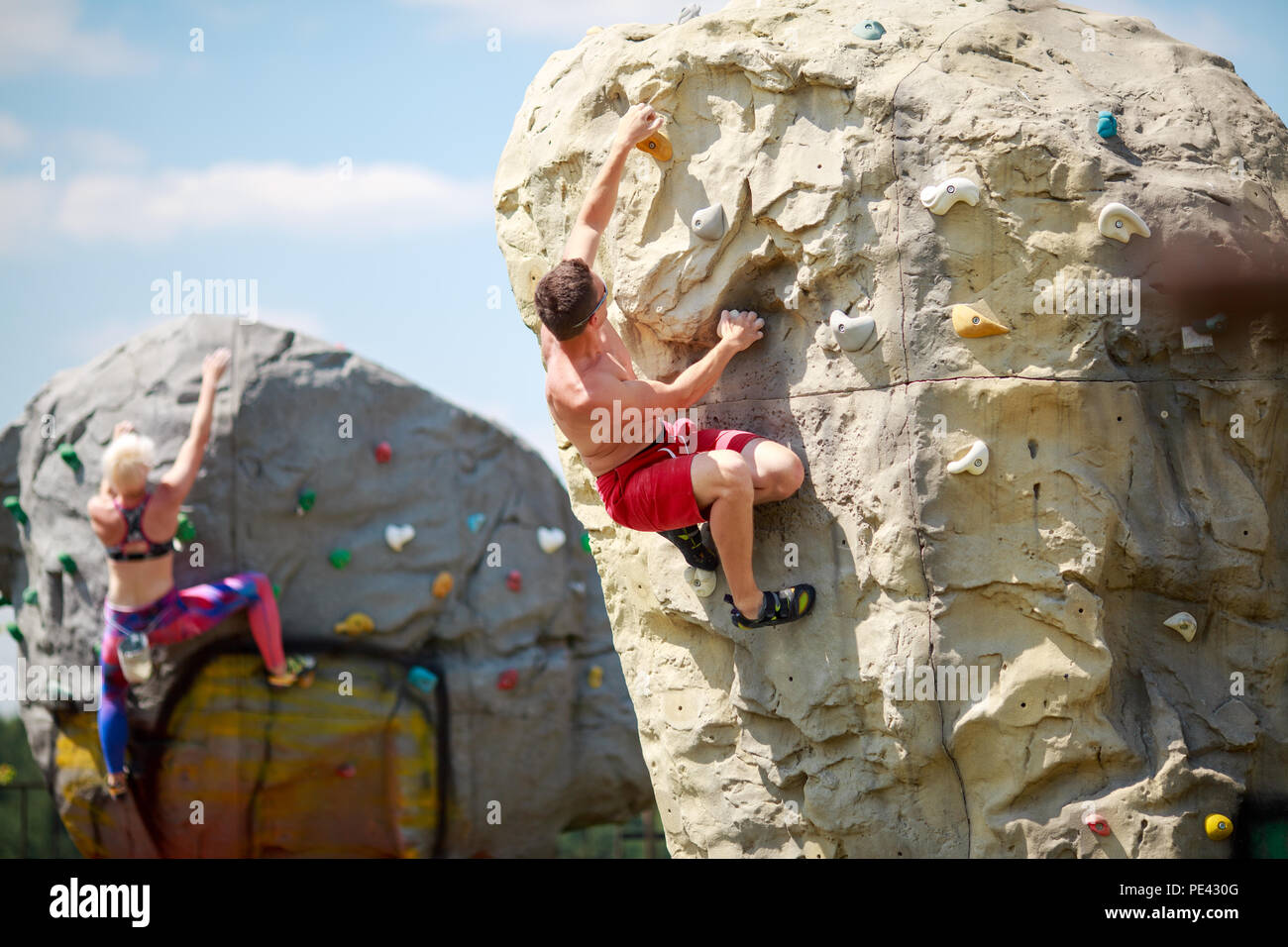 Foto von der Rückseite der Sport Kerl in roten Hosen und Frau auf Training  bei Klettern Felsbrocken gegen den blauen Himmel mit Wolken Stockfotografie  - Alamy