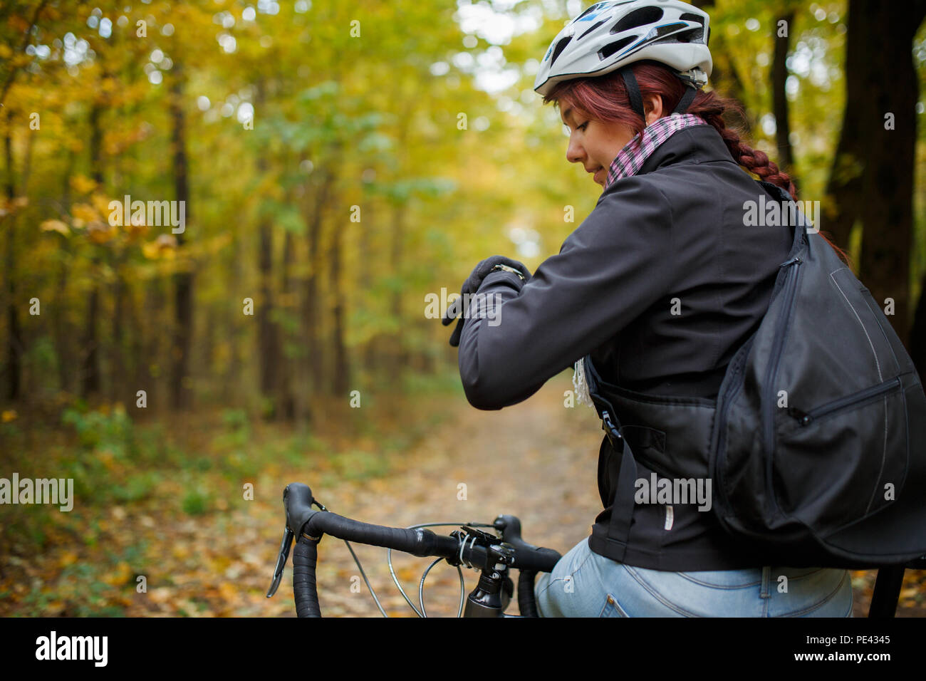 Foto von Smiling brunette in Helm sitzt auf Fahrrad im Herbst Stockfoto