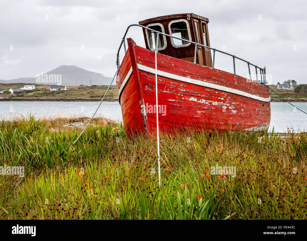 Red Fischerboot schleppte sich aus dem Wasser in Roundstone an der Küste von Connemara im Westen Irlands Stockfoto