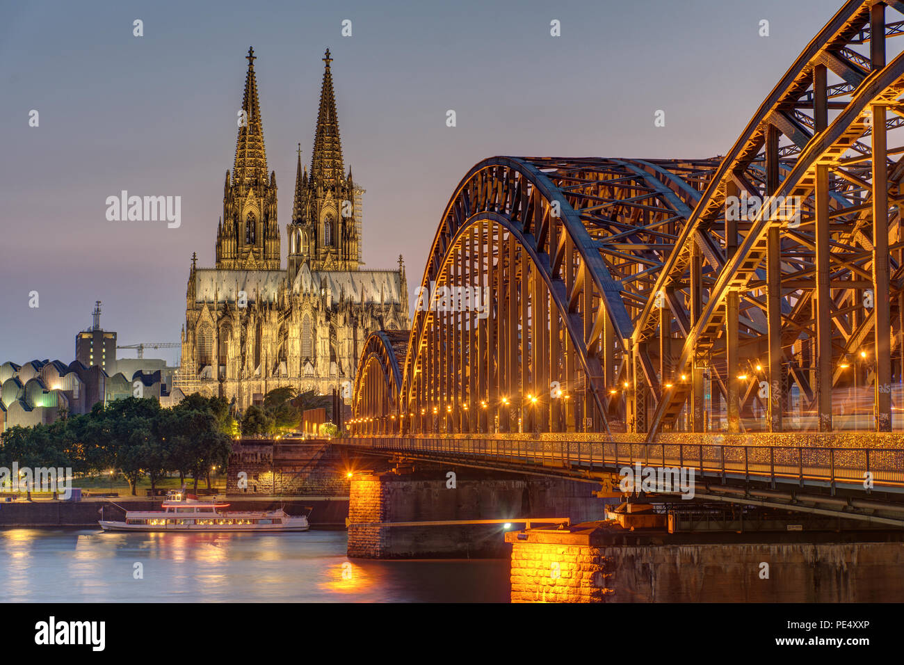 Die imposante Kathedrale von Köln mit der Hohenzollern Brücke über den Rhein bei Dämmerung Stockfoto