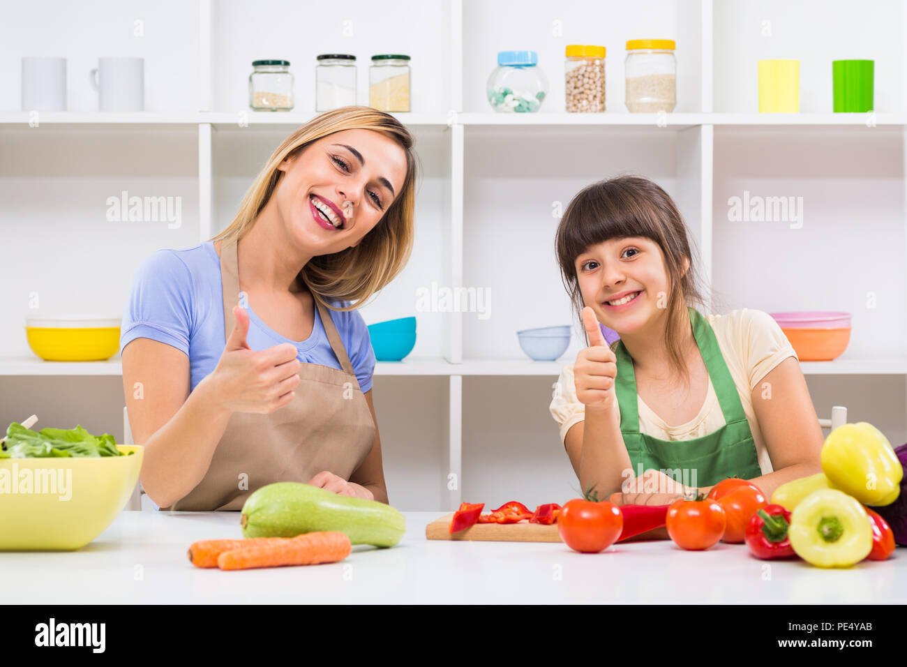 Glückliche Mutter und ihrer Tochter, Daumen hoch, während Sie genießen Sie gesunde Mahlzeit zusammen, an ihrem Haus. Stockfoto