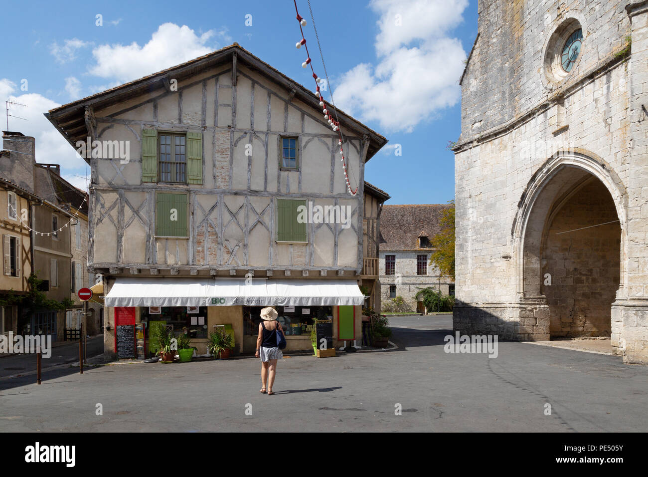 Ein Tourist in einem Geschäft und der Kirche; Issigeac, einem Bastide in der Dordogne, Frankreich Europa Stockfoto