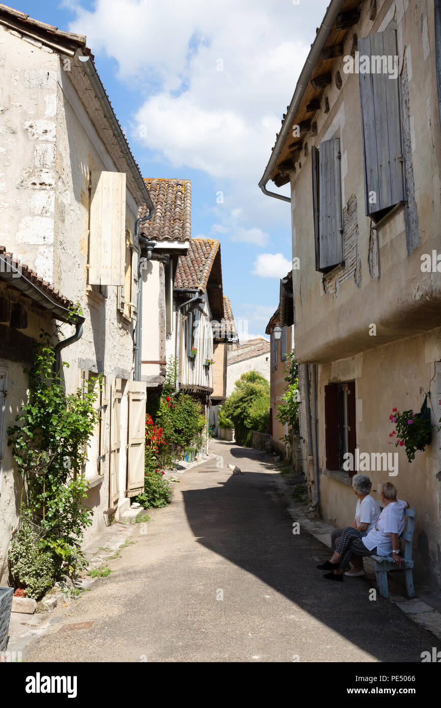 Zwei ältere Frauen in einer mittelalterlichen Straße sitzen, Issigeac Bastide, Dordogne Frankreich Europa Stockfoto